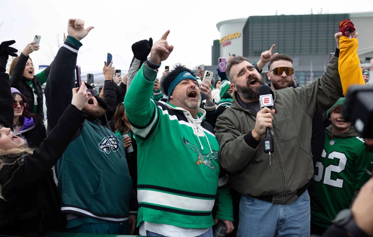 Former Philadelphia Eagles center Jason Kelce (right) leads fans in a cheer during a TV segment in the parking lot of Lincoln Financial Field.