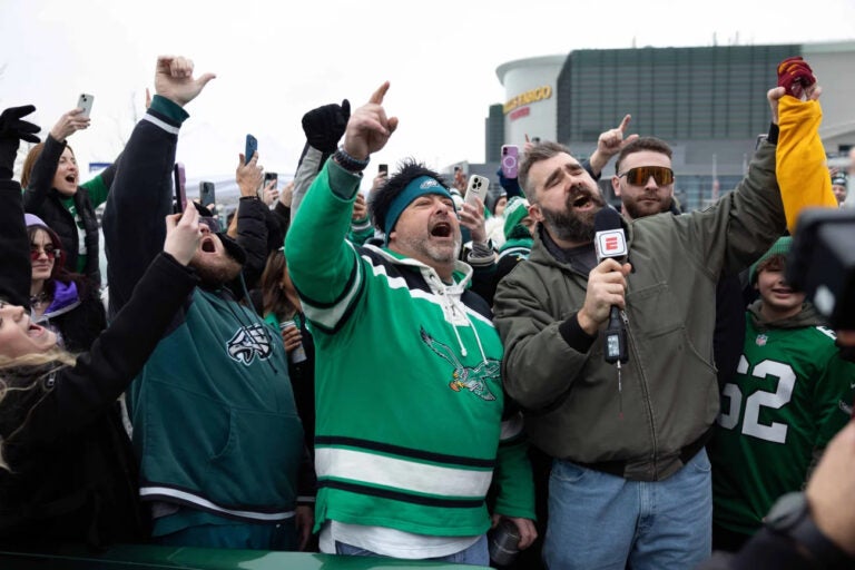 Former Philadelphia Eagles center Jason Kelce (right) leads fans in a cheer during a TV segment in the parking lot of Lincoln Financial Field.