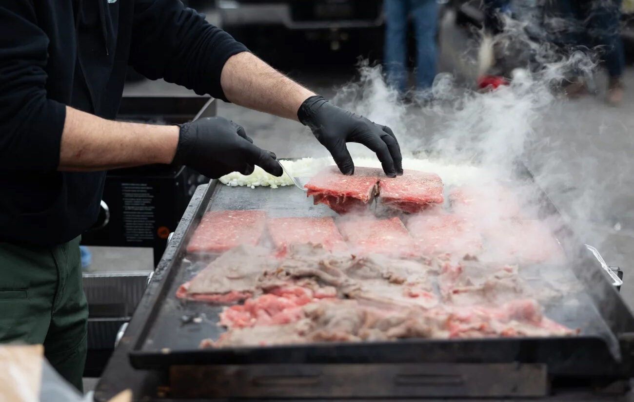 Chris Tsoubis prepares free cheesesteaks at the tailgate of Ed Callahan