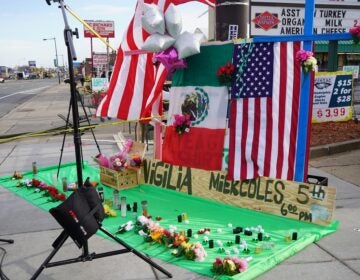 a memorial on the sidewalk for Nigilia Miekcoles 5th, with flags, flowers and candles