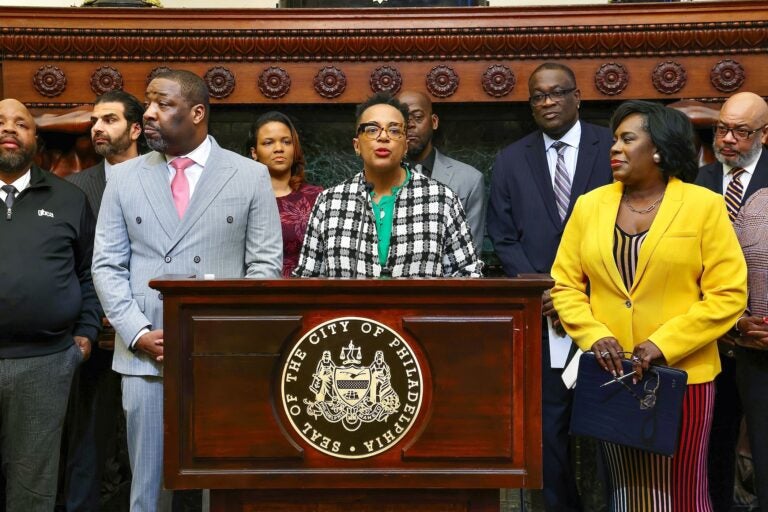 Angela D. Brooks speaking at a podium surrounded by other officials