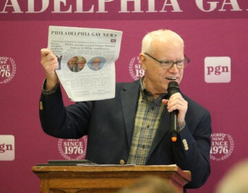 Ed Miller held up Thursday's copy of the Philadelphia Gay News with the front page story of the Elder Initiative at the William Way LGBT Community Center being honored during the LGBTQ Senior Summit. (Cory Sharber/WHYY)