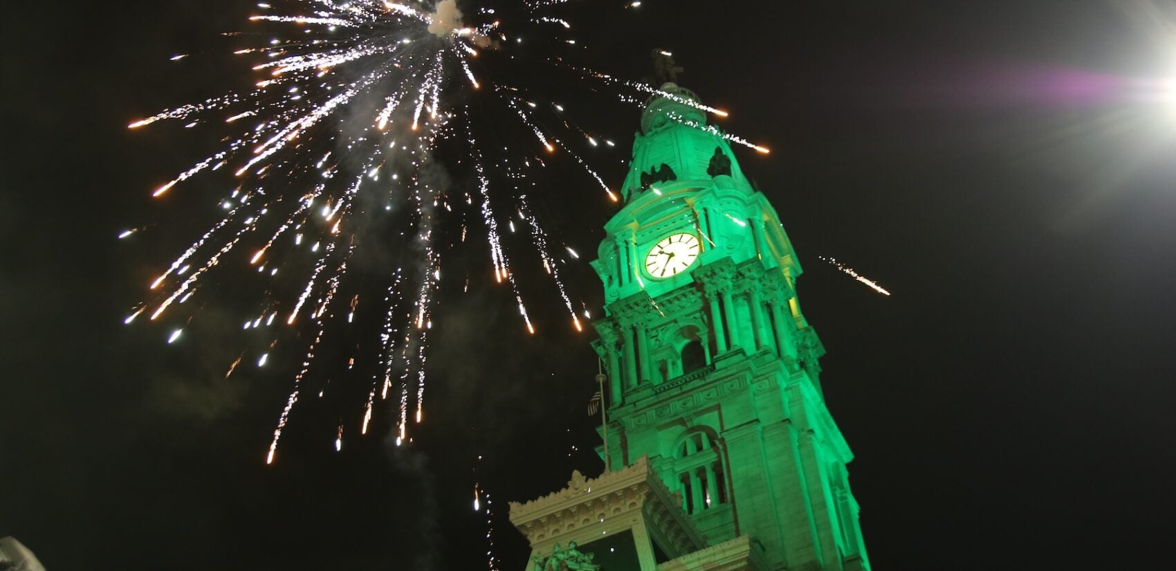 Fireworks over CIty Hall which is lit up in green light