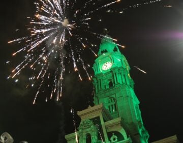 Fireworks over CIty Hall which is lit up in green light