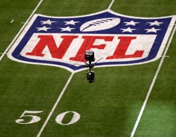 The NFL logo on the field and a camera seen in the air