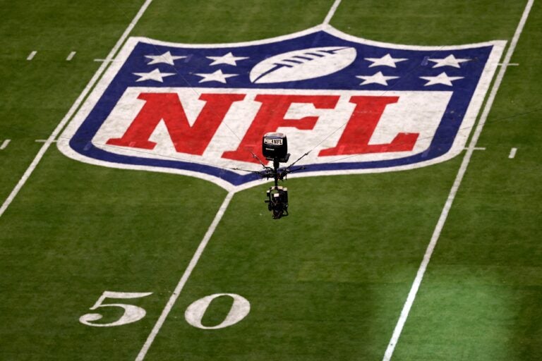 The NFL logo on the field and a camera seen in the air