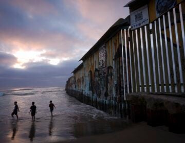 children playing on the beach near the border well which extends into the water