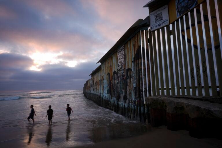 children playing on the beach near the border well which extends into the water