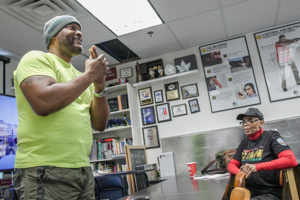 A man gestures to his class, teaching them gun safety