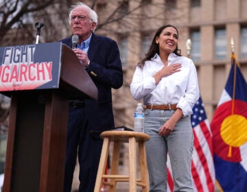 Sen. Bernie Sanders, I-Vt., left, speaks as Rep. Alexandria Ocasio-Cortez, D-N.Y., responds to calls of support during a stop of their 