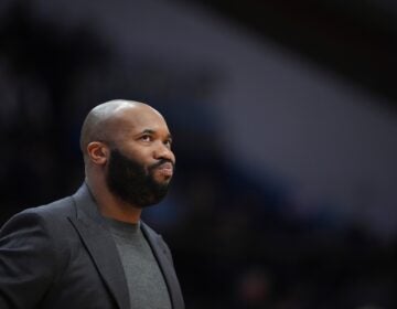 Kyle Neptune watches during an NCAA college basketball game