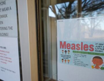 A sign on the door of a doctor's office with information about Measles