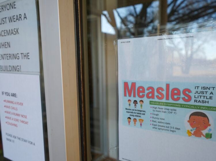 A sign on the door of a doctor's office with information about Measles