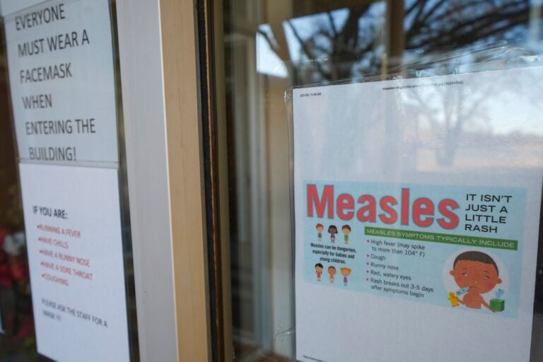 A sign on the door of a doctor's office with information about Measles