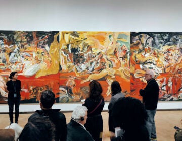 A woman explains a large painting to an audience