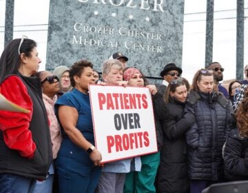 Crozer Health staff protesting with a sign reading PATIENTS OVER PROFITS