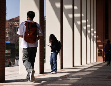 Students wearing backpacks are shown walking around a college campus