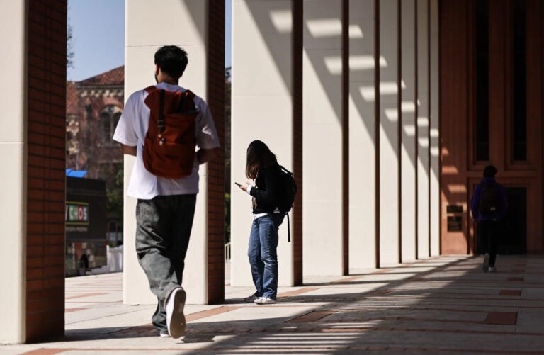 Students wearing backpacks are shown walking around a college campus