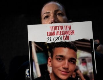 Yael Alexander holds a poster of her son, Edan