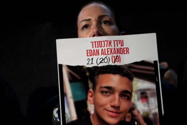 Yael Alexander holds a poster of her son, Edan