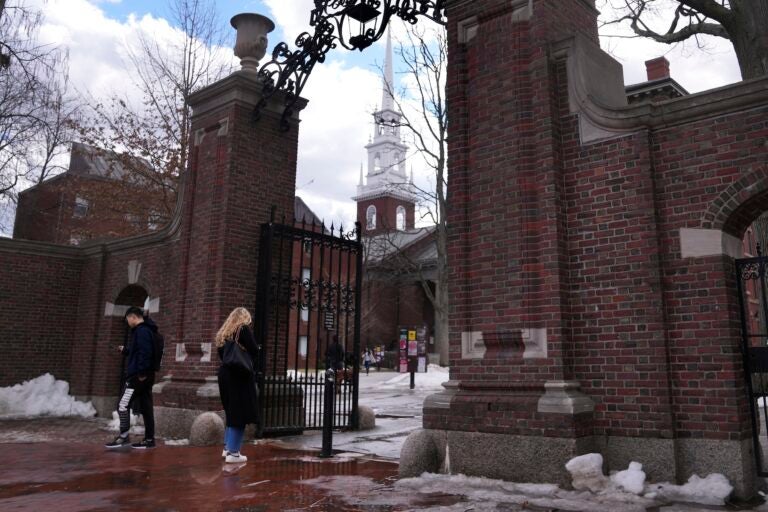 Pedestrians walk through the gates of Harvard Yard at Harvard University