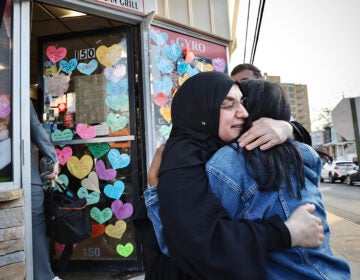 A restaurant owner previously detained by immigration enforcement officers hugs a neighbor in front of her restaurant