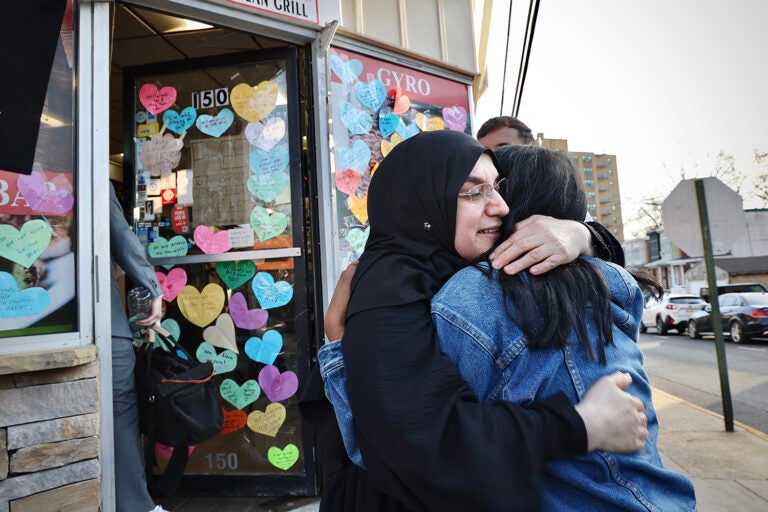 A restaurant owner previously detained by immigration enforcement officers hugs a neighbor in front of her restaurant