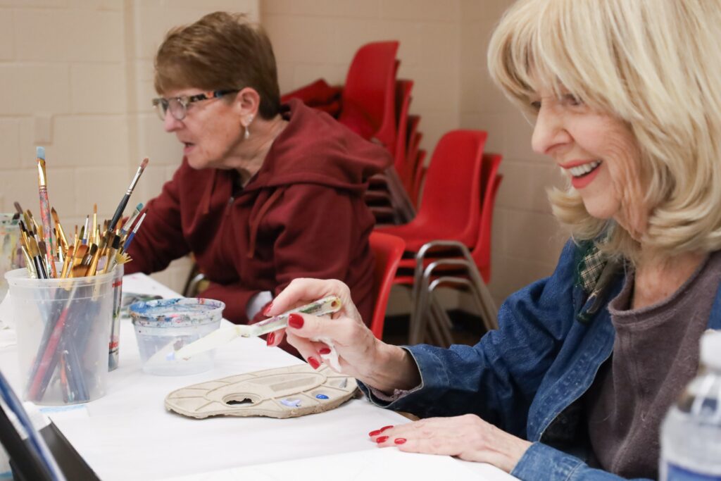 Two women laughing and working on art projects