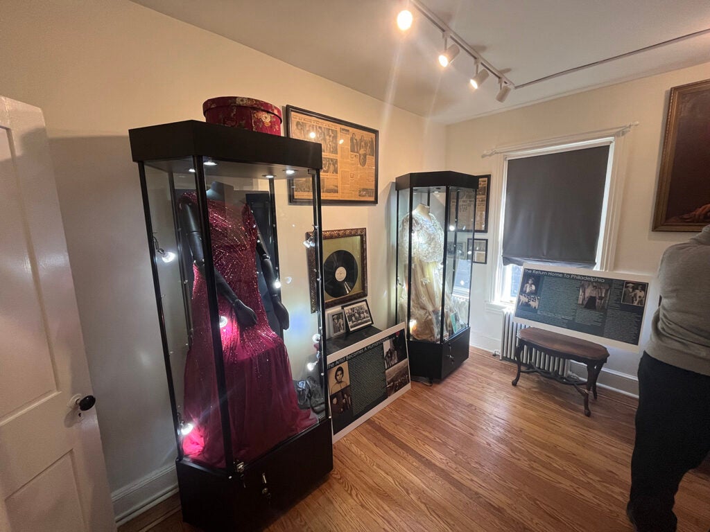 A red dress, vinyl record and other objects sit on display inside a museum