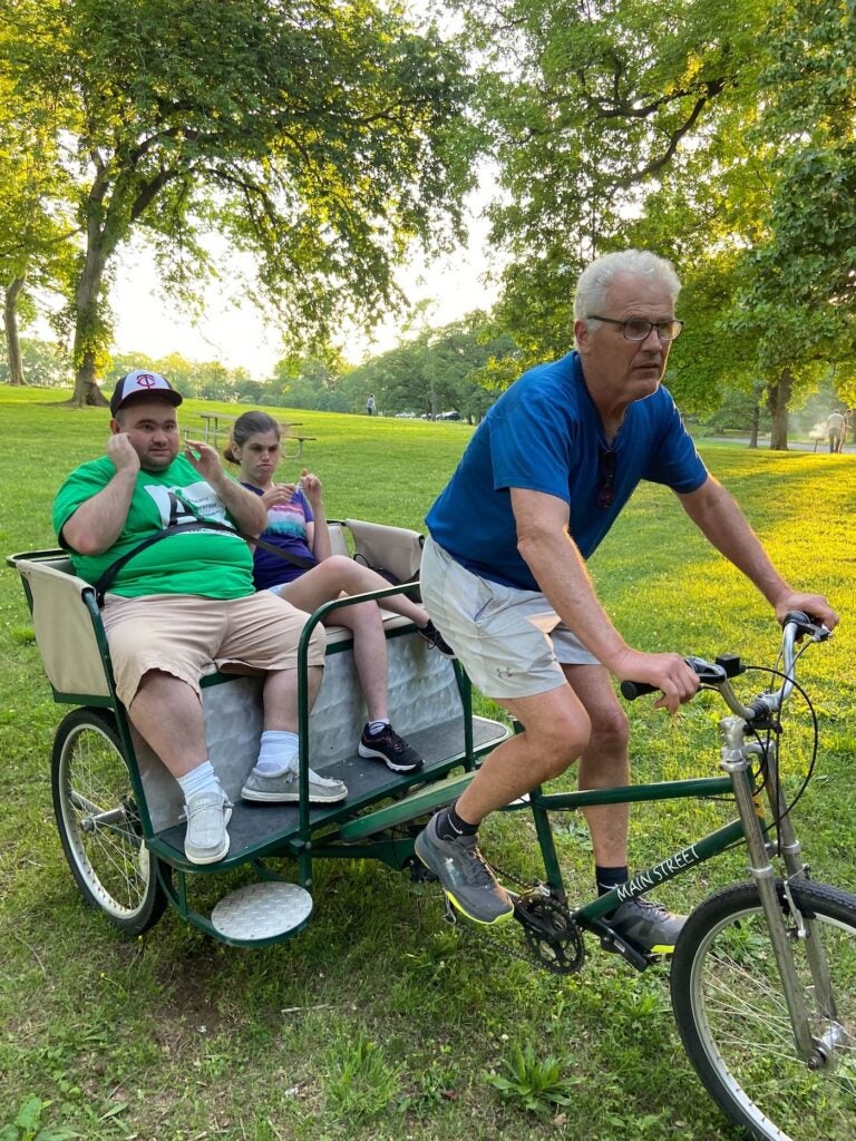 2 people getting pulled by a man on a bike