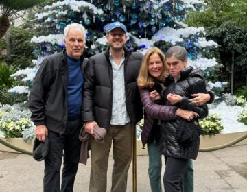 A. family posing in front of a very large decorated tree