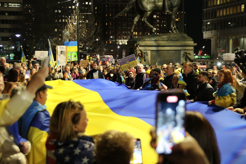 People hold a large Ukrainian flag during a protest outside of City Hall in Philadelphia