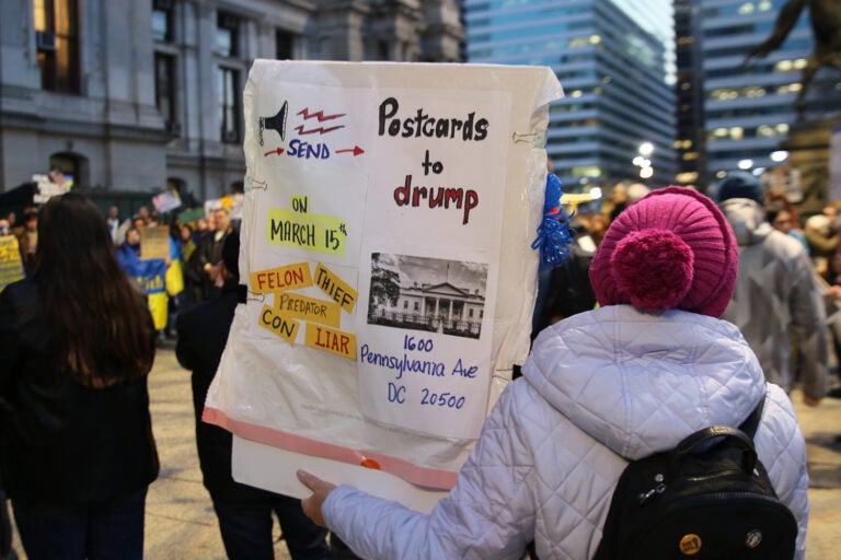 A person holding a sign protesting Trump stands outside City Hall in Philadelphia