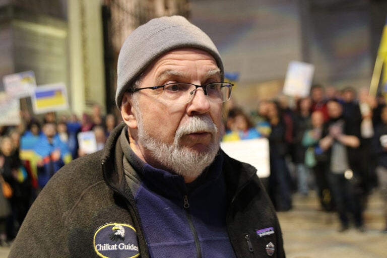 A man wearing a beanie stands outside City Hall in Philadelphia during a protest against President Donald Trump