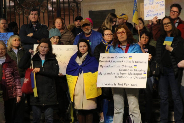 A woman holds up a sign saying she and her family are from Ukraine, which is 