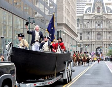 Actors portraying George Washington and his crew on the boat crossing the river, being driven down Broad Street during a parade