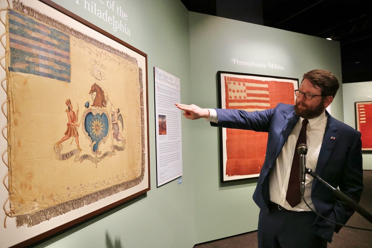 2024 04 17-e lee-james taub-philadelphia museum of the american revolution-banners of liberty curator James Taub, associate curator at the Museum of the American Revolution, points at flag on display in the museum
