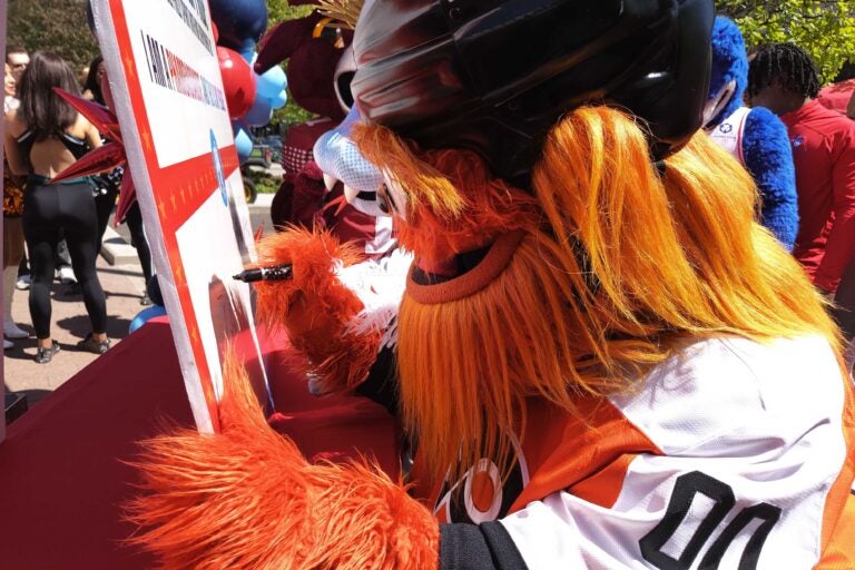 Gritty signs the pledge during the pep rally about volunteering in Philly for the semiquincentennial