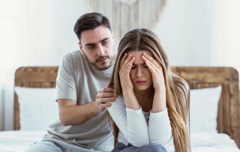 bigstock-Relationship-Of-Family-Proble-390318452 A woman distressed with her head in her hands while a man tries to console her.