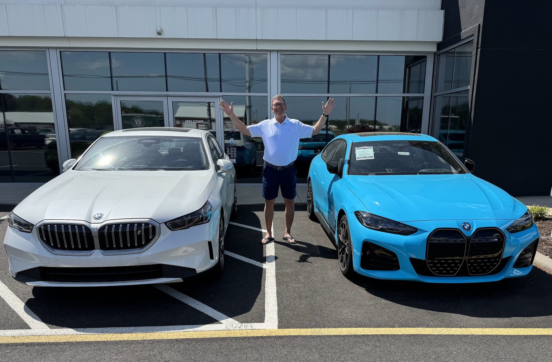 Car dealer Charlie Burton shows off two of the electric BMWs at his dealership in Milford.