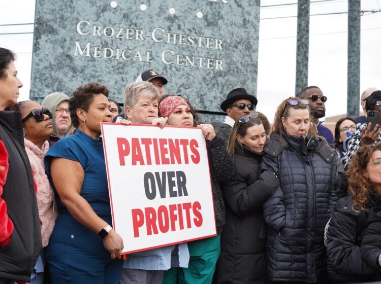 Crozer Health staff protesting with a sign reading PATIENTS OVER PROFITS