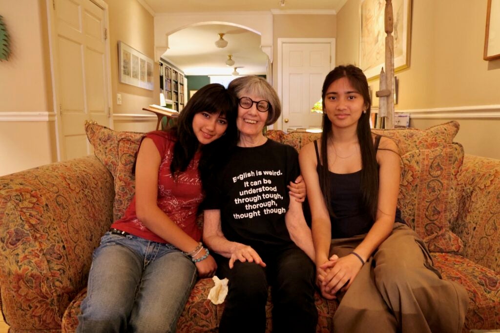 Gaia Bhullar (left), with her sister Malaika Bhullar (right), sit with their neighbor, Pam Riley (center) in living room