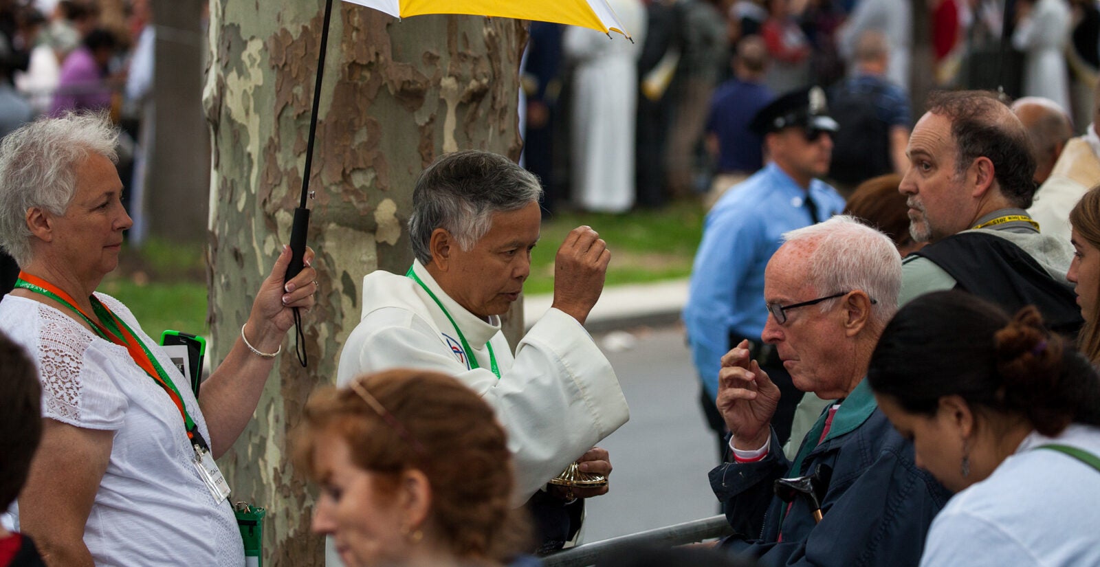 Taking communion on the Ben Franklin Parkway. (Brad Larrison/for NewsWorks) people in a crowd take communion