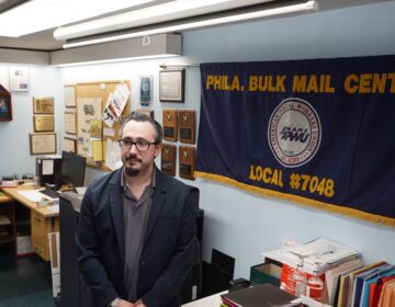 James DeRidder standing in front of postal workers union flag