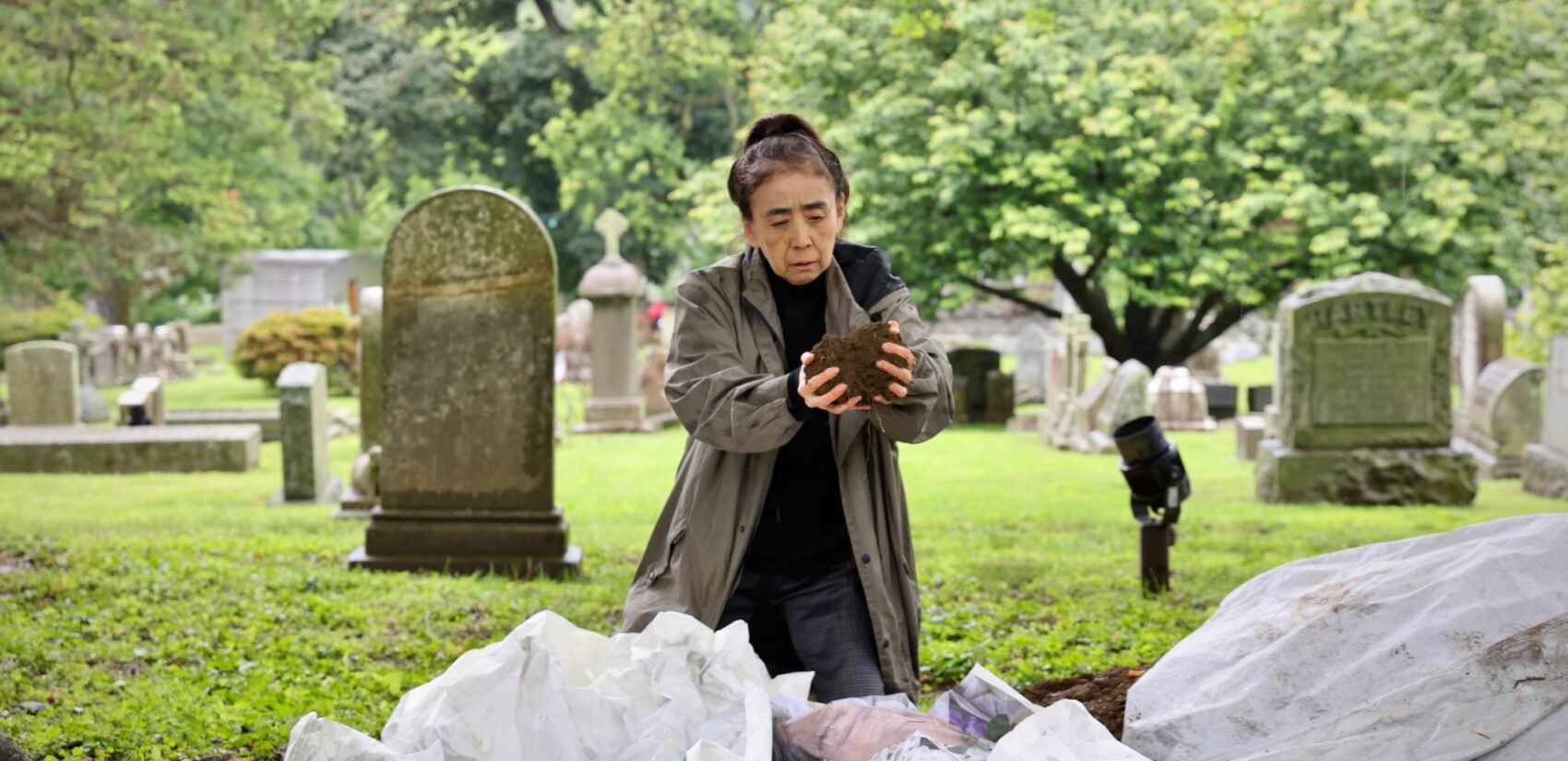 2025 05 28-e lee-eiko atake-philadelphia laurel hill cemetery-a body in places dirt Eiko Otake scatters dirt over an image of her mother at Laurel Hill Cemetery for the Death and Arts Festival