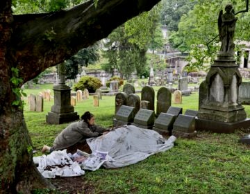 Eiko Otake scatters dirt over an image of her mother at Laurel Hill Cemetery for the Death and Arts Festival