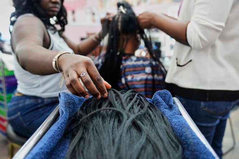 Trump Tariffs Black Hair Care A braider picks up pieces of synthetic braiding hair