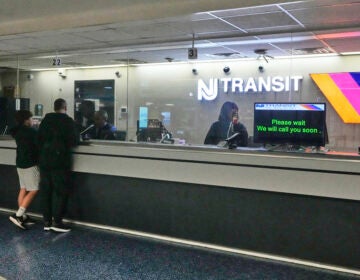 People stand at the train ticket counter of NJ Transit at Penn Station
