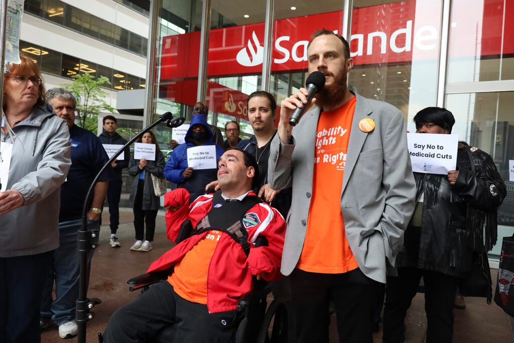 A man speaks into a microphone at a rally against Medicaid cuts in Philadelphia