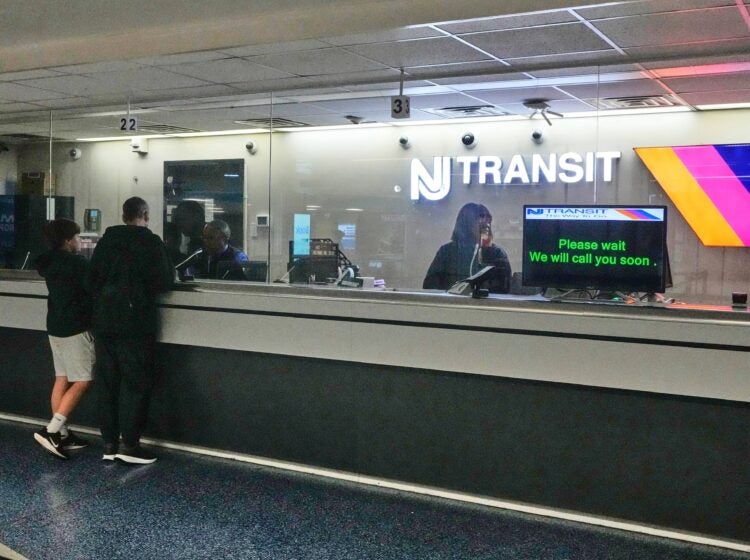 People stand at the train ticket counter of NJ Transit at Penn Station